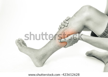 Young man holding his calf muscle in pain, isolated on white background, monochrome photo