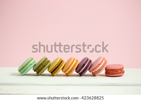 Sweet and colorful french macaroons or macaron on white wooden table pink background, Dessert. Minimal concept.