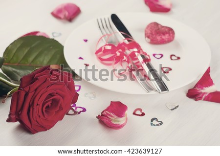 Romantic table setting with roses plates and cutlery .Toned photo