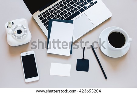 Creative flat lay photo of workspace desk with laptop, blank card, coffee, tag, smartphone and camera on grey background
