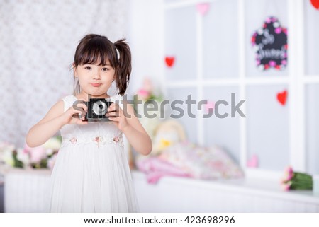 cute little girl holding an old camera. child taking pictures on an old camera