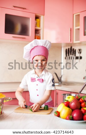 portrait of little boy in the hat of the chef and an apron. Little chef cooks in the kitchen.Portrait of cute boy helping at kitchen  cutting ingredients for salad.