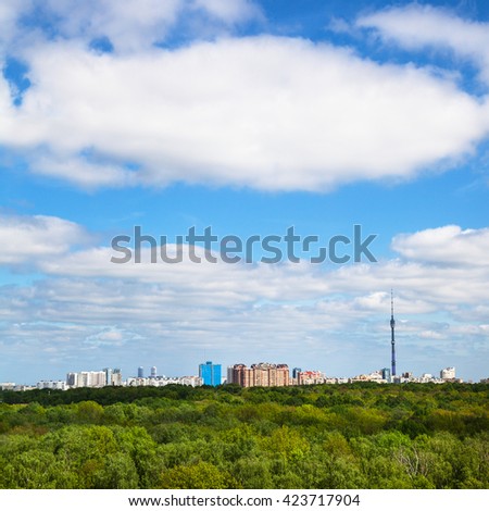 green trees and city buildings on horizon under blue sky with white clouds in summer day
