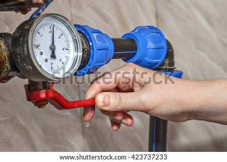 Water gauge pressure, hand shut off main valve, close-up. Royalty-Free Stock Photo #423737233