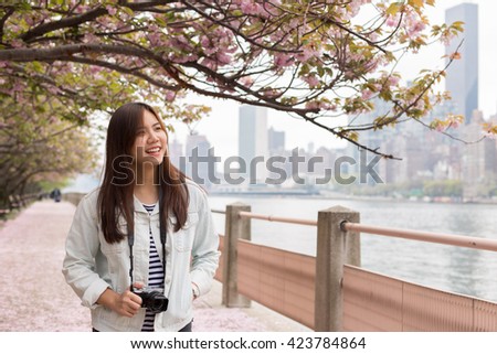 Young Female Tourist Walking under Cherry Blossom Trees in Roosevelt Islands, NYC