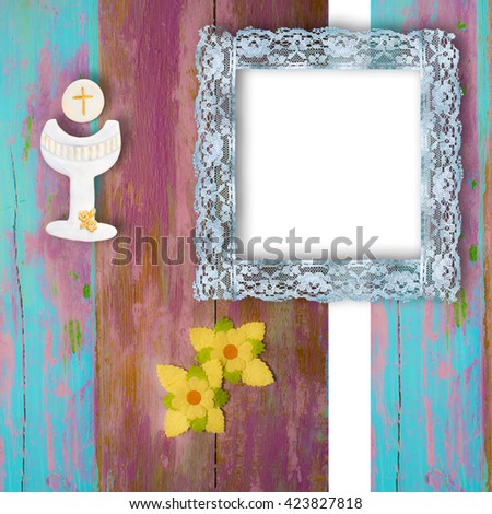 First Holy Communion photo frame invitation, chalice and flowers on wooden background