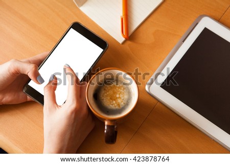 Female hands with smartphone with copy space on screen and cup of coffee.  Fingers zooming in picture on screen. Social network concept.