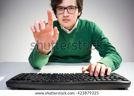 Concentrated young man pointing at something with finger and using computer keyboard