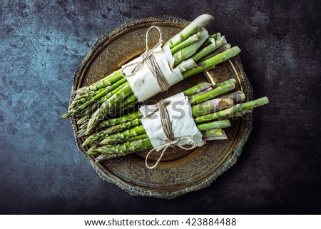 Top of view bunch of fresh asparagus on wrought plate. Royalty-Free Stock Photo #423884488
