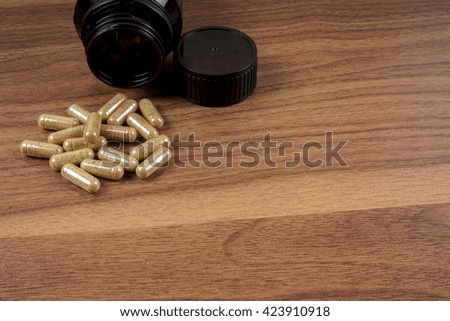 Gray  pills and pill bottle on wooden background. DOF and copy space.