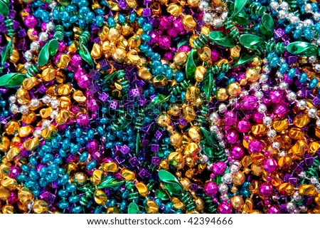A background of colorful mardi gras beads including gold, blue, green, pink and purple