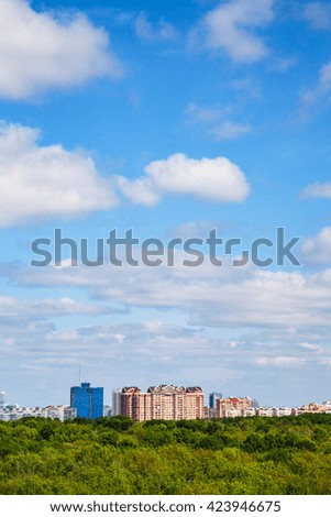 apartment houses and green forest under cloudy blue sky in summer day