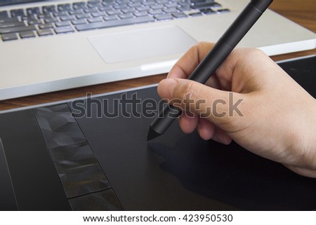 close up of graphic designer hand using a pen on tablet with notebook computer.