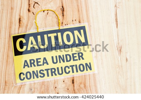 closeup the sign Caution area under construction on wood background