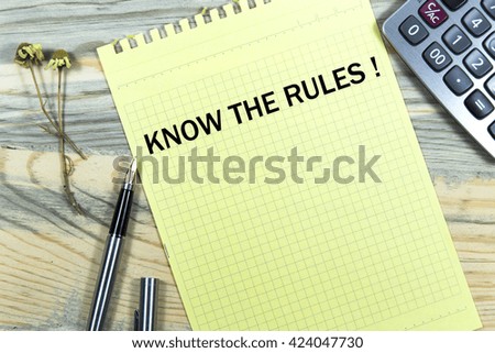 know the rules writing in notebook pen and calculator wooden desk.