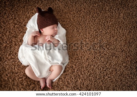 
Serene newborn baby sleeping wrapped in diaper with funny woolen hat  Royalty-Free Stock Photo #424101097