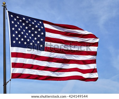 American flag USA stars and stripes on flagpole in the wind with blue sky and clouds