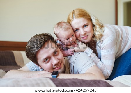 Beautiful happy couple and their baby relaxing in a bed together