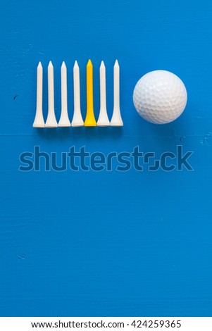 Golf ball and wooden golf tees on the wooden blue desk