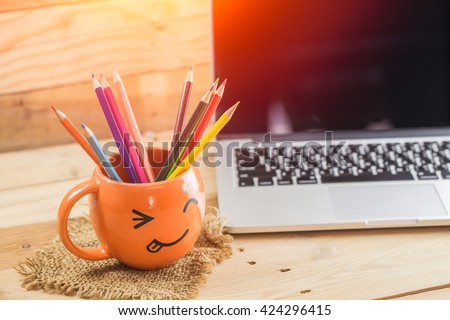 laptop with smiley wrinkle happy face mug and color pencil on wood background, digital working creative idea happy with idea digital artist concept.