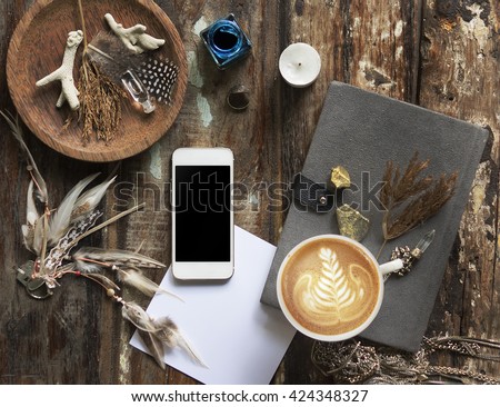 Boho crack background for mockup with cup of cappuccino and smartphone. Desk for artist, painter. Copy space. Natural, rustic, ethnic or hipster vintage mock up. Top view. Shabby chic style workplace 