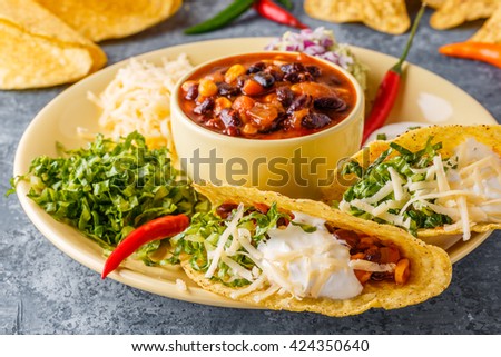 Tacos with chili con carne, salad, cheese and sour cream, selective focus.