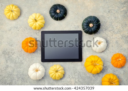 Cooking and technology. Tablet computer with collection of fresh pumpkins on the grey background. Top view.