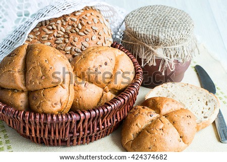  Wicker basket with bread and a clay pot on a napkin on a light wooden background.