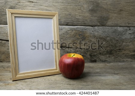 Wood photo frame and red apple on wooden table