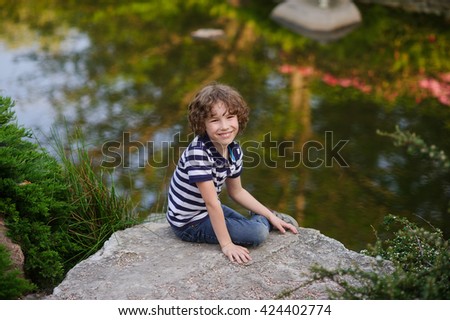 Boy sits on a large boulder at the lake