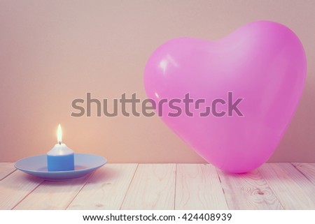 Pink heart balloon and a candle on the wooden floor with brown paper for background. (vintage or retro style)