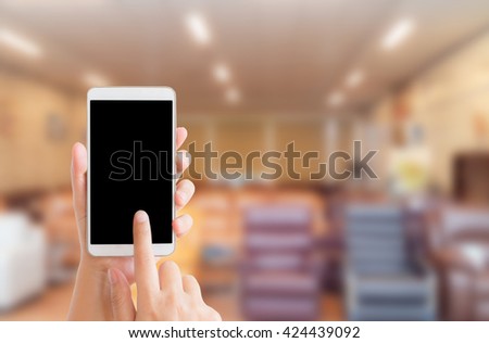 woman use mobile phone and blurred image of furniture shop in the mall