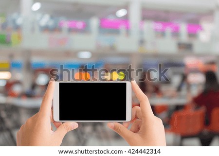 woman use mobile phone and blurred image of cafeteria in the university with beautiful bokeh from the light