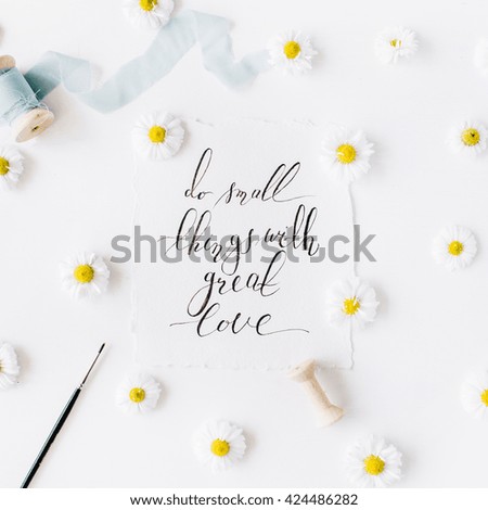 quote "Do small things with great love" written in calligraphy style on paper with chamomile buds and blue ribbon. Flat lay, top view