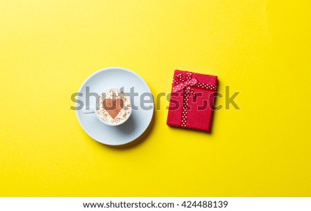 blue cup of coffee and red gift on the yellow background
