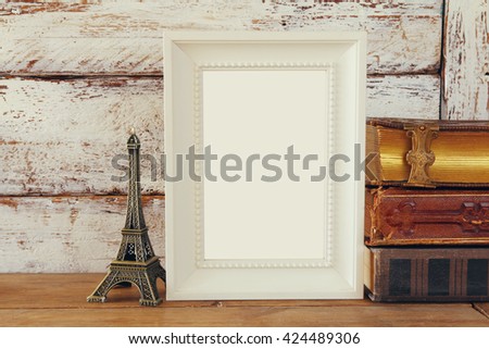 image of blank wooden frame, next to old books. template, ready to put photography. vintage filtered
