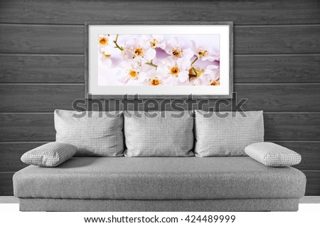 Interior decor mock up, frame with cherry flowers picture over the sofa, at wooden wall