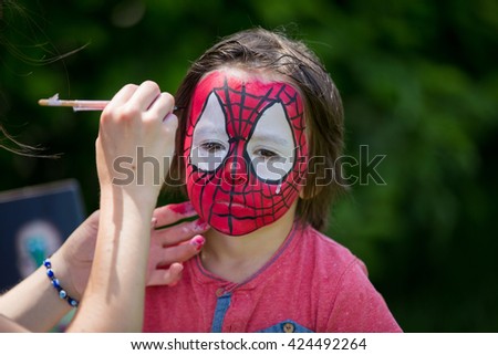 Cute little five years old boy,. having his face painted as spider on his birthday party