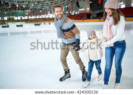 Smiling family at ice-skating rink Royalty-Free Stock Photo #424500136