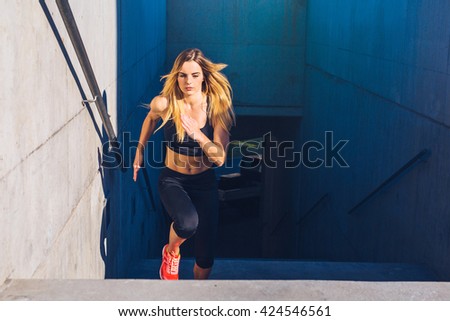 Female athlete running fast up the stairs - staircase workout Royalty-Free Stock Photo #424546561