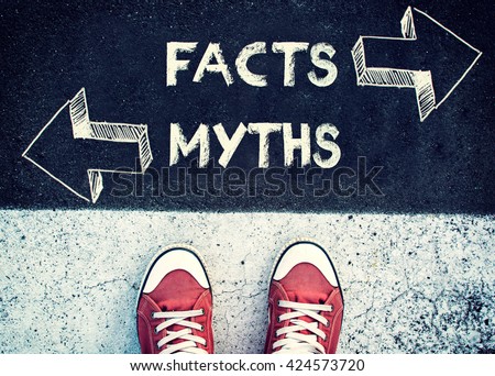 Student standing above the sign Facts and myths Royalty-Free Stock Photo #424573720
