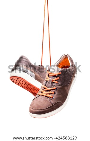Pair of casual sport leather shoes hanging isolated on white background, Orange shoelace