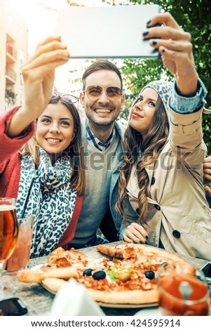 Group of young people laughing and doing a selfie in cafe