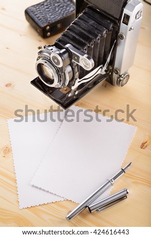 Old retro vintage camera and old photos with rough edges on wooden table
