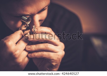 Portrait of a jeweler during the evaluation of jewels. Royalty-Free Stock Photo #424640527