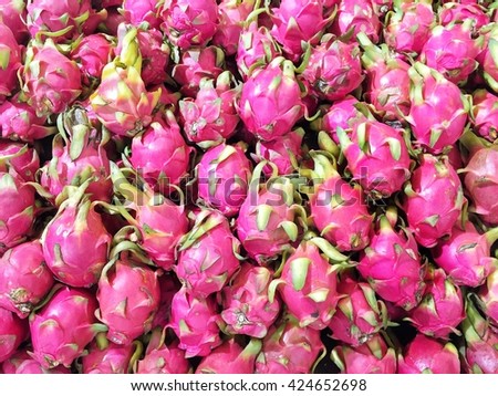 Pile of raw dragon fruit with skin for sale in market - background