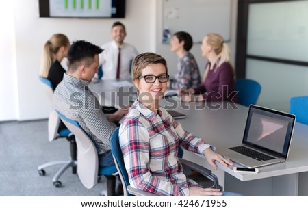 portrait of young business woman at modern startup office interior, team in meeting group in background