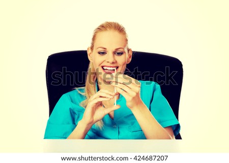 Funny female doctor or nurse sitting behind the desk and holding syringe