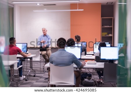 handsome mature teacher and students in computer lab classroom Royalty-Free Stock Photo #424695085