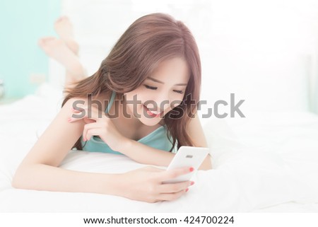 Health woman Smile use smart phone and she lying on the bed at home , asian girl